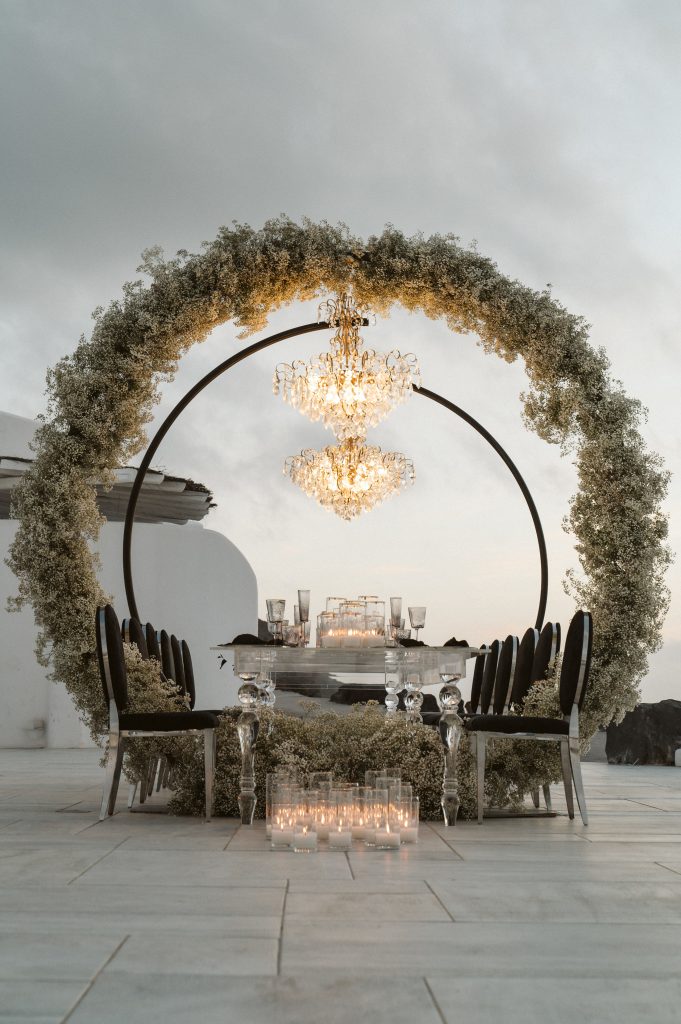 A wedding dinner table is adorned with crescent stands and chandeliers, creating a captivating and enchanting atmosphere for the celebration.