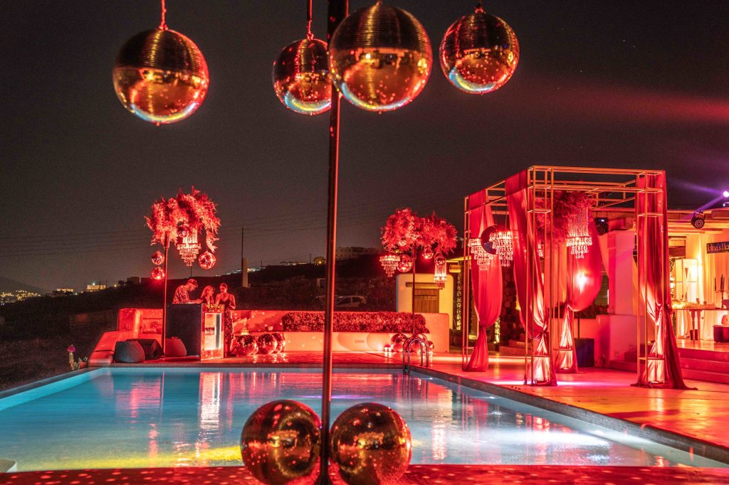 A bachelorette party turns glamorous with disco balls, vibrant lights, mandap canopy, and elegant chandeliers, creating an unforgettable celebration.